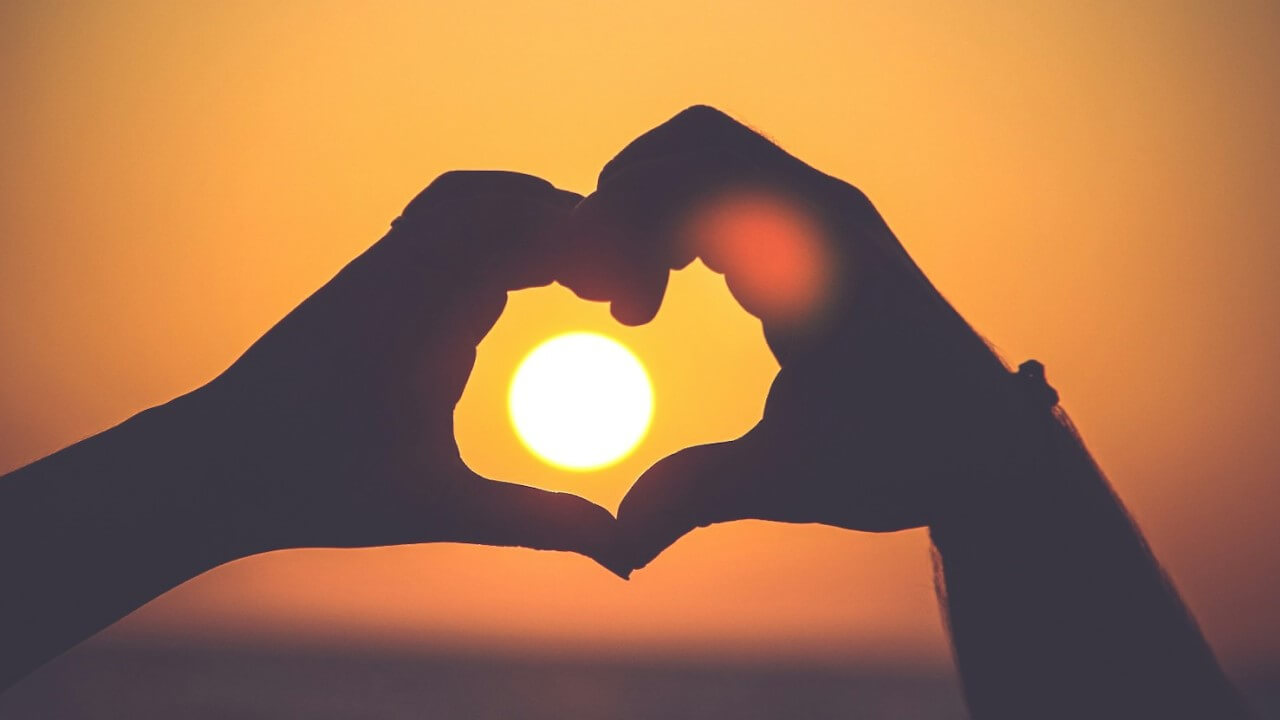 married-couple-makes-a-heart-against-the-sunset